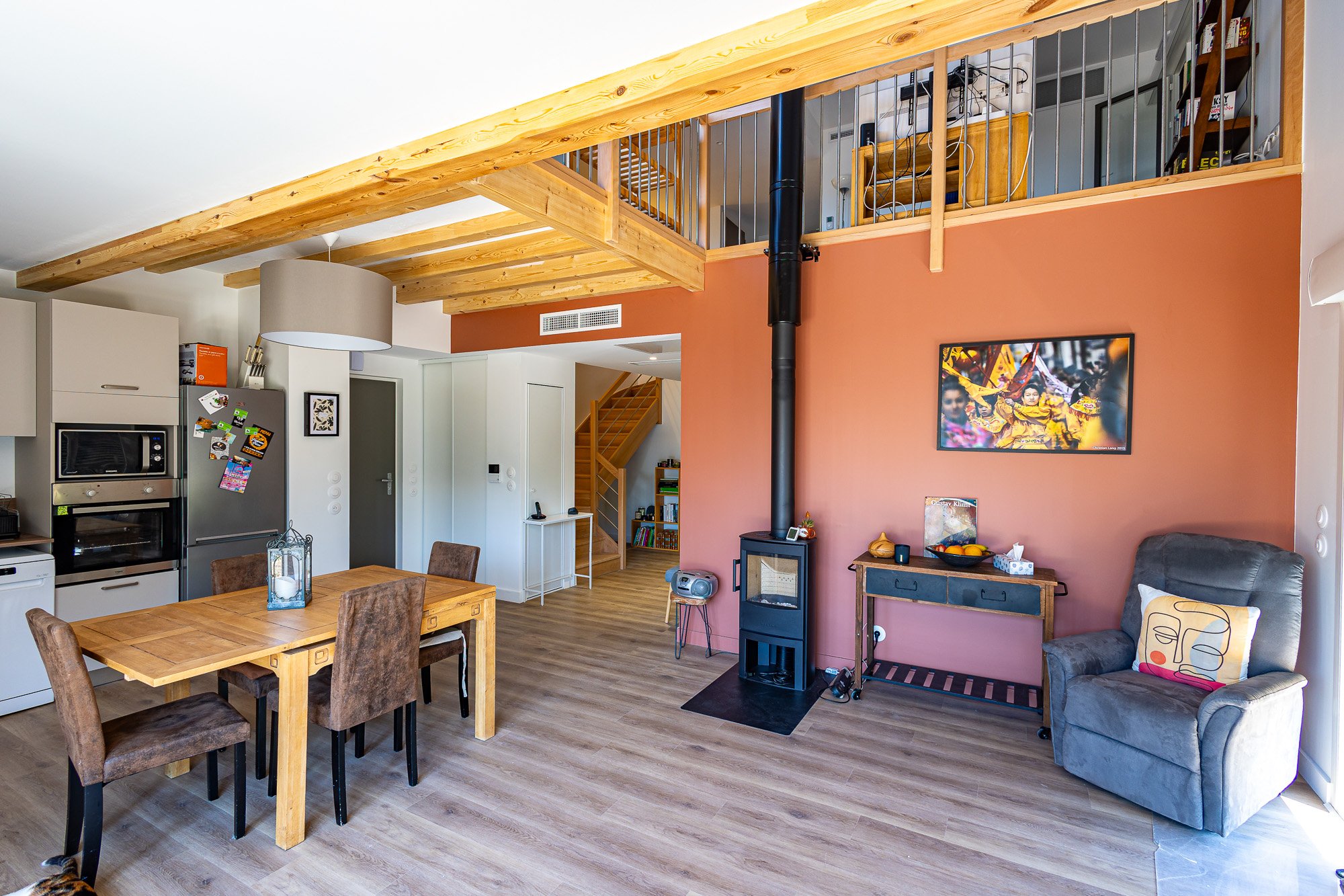Pièce à vivre avec mur terracotta, poêle à bois et mezzanine