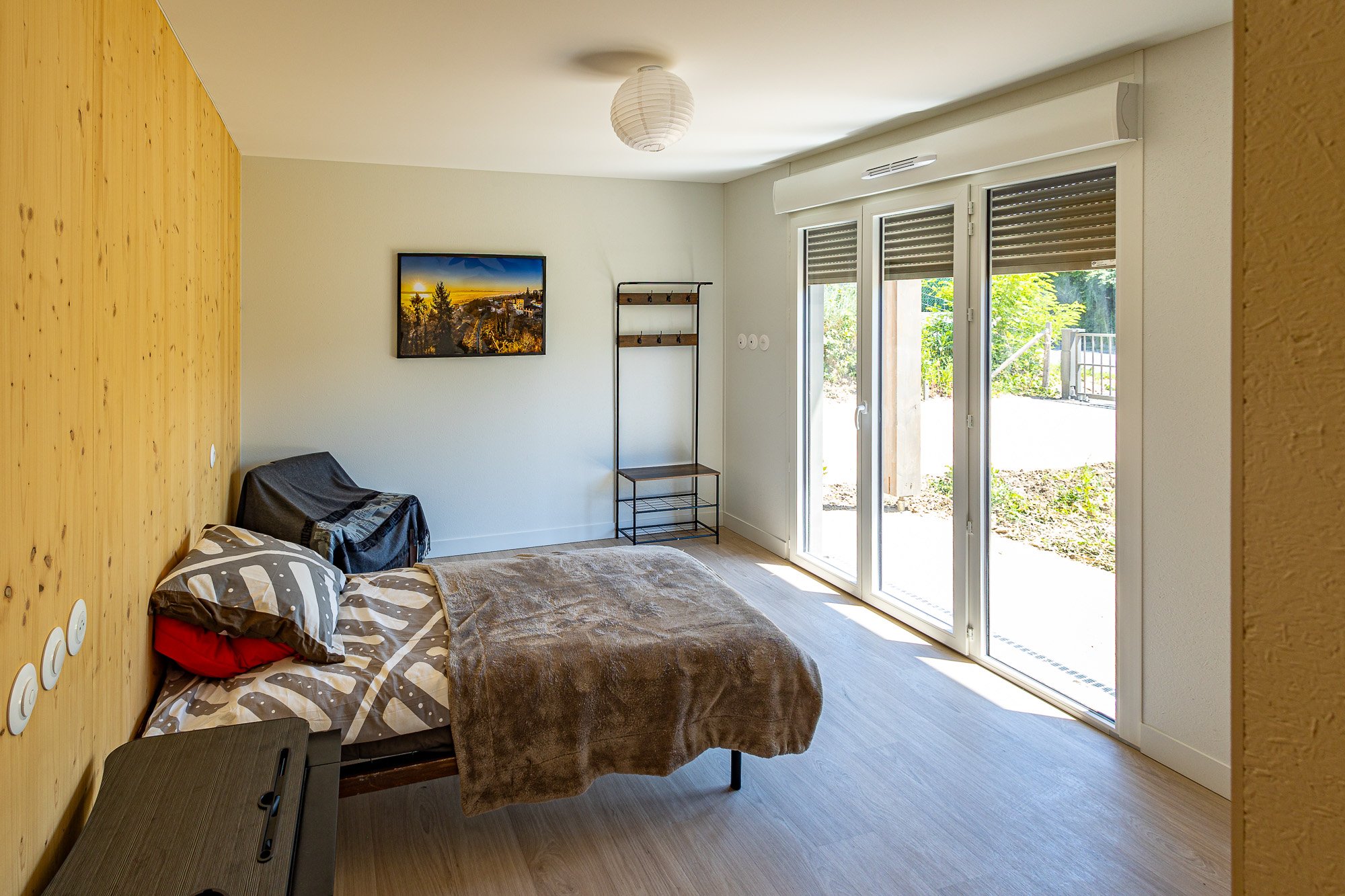Chambre avec mur bois, lit et vue jardin
